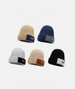 Detail view of five multi-color knit beanies with fleece lining and leather fashion labels