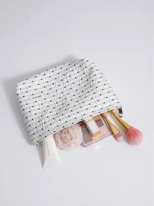Beauty case minimalista a pois bianchi mostrato con pennelli e cosmetici