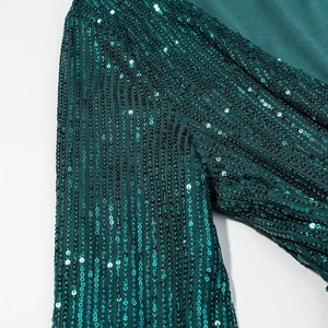 Detailed macro view of dark green sequins on mesh fabric for a V-neck evening dress