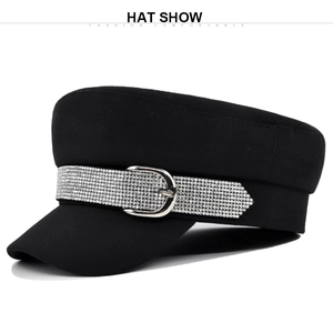 Detail of a black flat-top military hat featuring a sparkling rhinestone buckle decoration