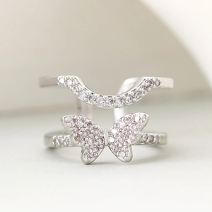 Silver butterfly knuckle ring set with sparkling zircons on minimalist grey background
