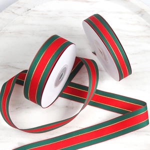 Close-up of red and green ribbed ribbons with gold trim on white marble