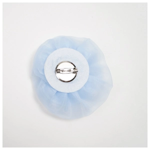 Back view of light blue organza rose brooch with silver safety pin on white background
