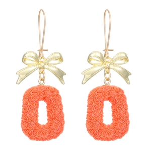 Détail de boucles d'oreilles nœud doré avec pendentifs ovales rose corail à motif rose