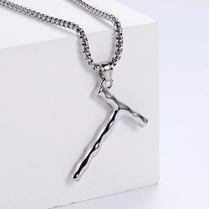 Détail macro du pendentif T argenté style lave sur une chaîne à billes en métal poli