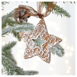 Star-shaped gingerbread ornament with white lace patterns hanging on a snowy Christmas tree