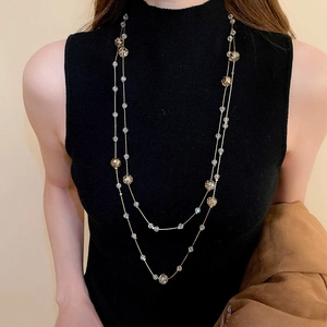Close-up of elegant double-layered crystal bead necklace worn over a black sweater