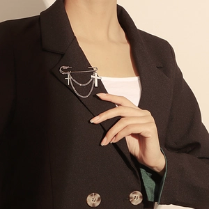 Silver cross pendant brooch with chain on black suit lapel for a stylish look