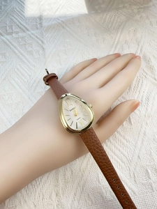 Close-up of golden snake-head watch with brown leather strap on model wrist