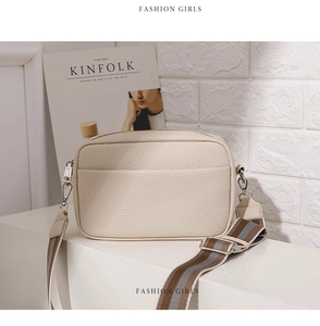 Detail of beige litchi pattern PU leather crossbody bag with striped woven strap