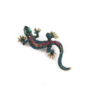 Detailed close-up of retro lizard brooch with teal and magenta rhinestones on gold base