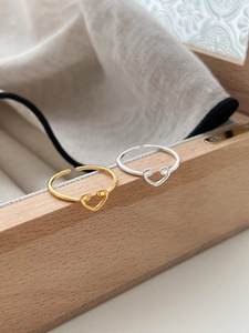 Close-up of gold and silver heart-shaped adjustable rings on a wooden jewelry box