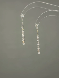Close-up of long linear earrings with sparkling crystals and elegant white pearls