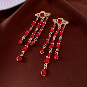 Detailed view of vintage gold tassel earrings with red gems and crystal rhinestones