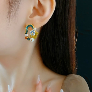 Close-up of vintage flower earrings with blue enamel, pearls and crystals on ear