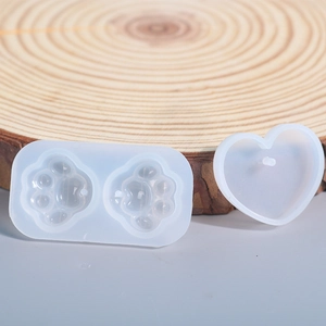 Detail view of silicone DIY resin molds in cat paw and heart shapes on wood