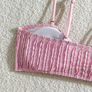 Detailansicht des rosa gesmokten Bikini-Oberteils mit verstellbaren Trägern und Textur