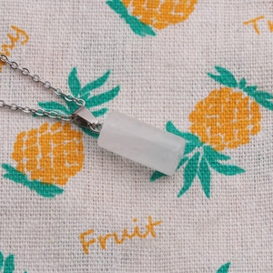 Close-up of a white translucent stone cylinder pendant on a silver metal chain