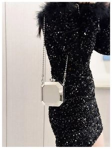 Detail of silver octagonal metal evening clutch bag with slim ball chain on model