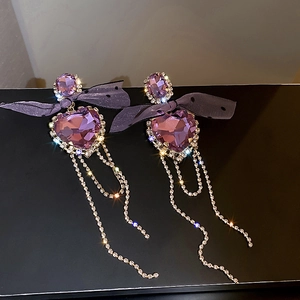 Macro detail of luxury purple crystal bow earrings with rhinestone fringe tassels