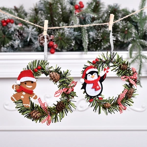 Christmas wreath ornaments with gingerbread man and penguin motifs on festive pine needles