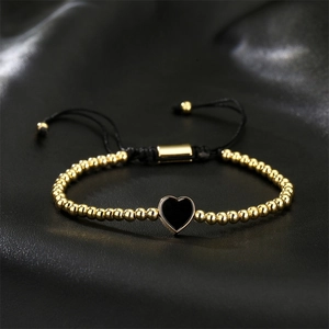 Detail der Goldperlen und des schwarzen Herzanhängers am gewebten Armband