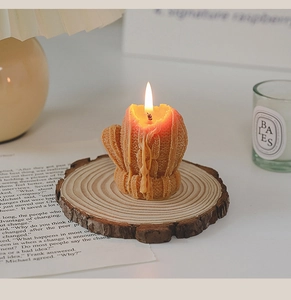 Macro shot of burning cactus-shaped scented candle on a minimalist round wooden base