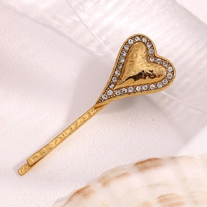 Detailed macro view of an 18K gold-plated heart hair clip with sparkling rhinestones