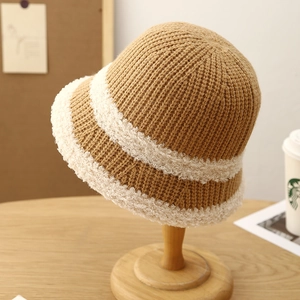 Macro detail of the warm brown knitted bucket hat featuring white fleece stripe accents