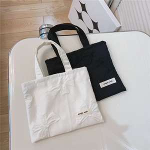 Detail of mini tote bags featuring 3D bow texture and simple wish label on canvas