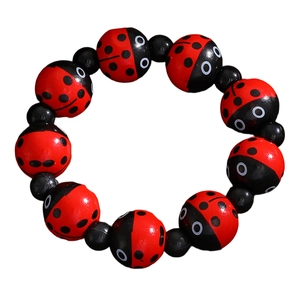 Vue détaillée des perles en bois coccinelle rouge et entretoises noires sur le bracelet