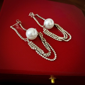 Macro shot of silver drop earrings with large pearls and sparkling diamond chain tassels