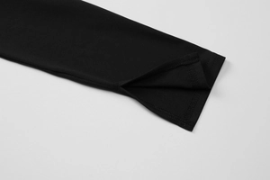 Dettaglio della manica di un abito nero con spacco laterale e cuciture precise