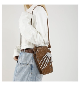 Detail of coffin-shaped brown PU leather crossbody bag with white skeleton hand and studs