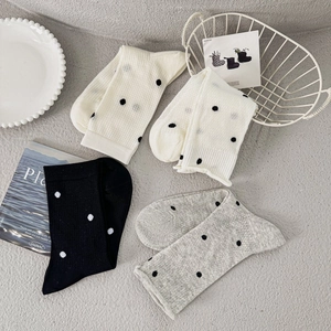 Detail showing white, black, and grey polka dot crew socks with fine knitted texture