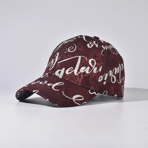 Detailed close-up of wine red baseball cap featuring silver cursive street art patterns