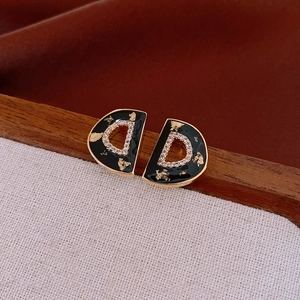 Close-up of vintage gold D-letter earrings with black enamel and sparkling zircons