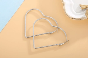 Detail of silver heart hoop earrings featuring unique textured surface and secure clasp