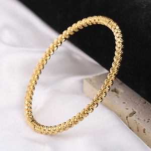 Detail of 5mm gold stainless steel bangle with twisted flower texture on velvet