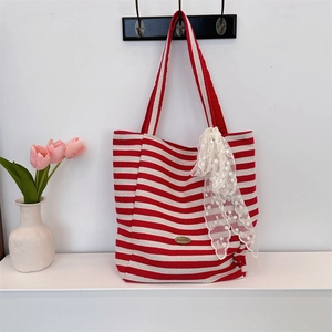Close-up of red and white striped canvas tote bag with lace detail and metal tag