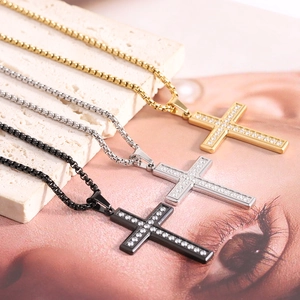 Detailed shot of three cross pendants in gold, silver, and black with shiny clear crystals