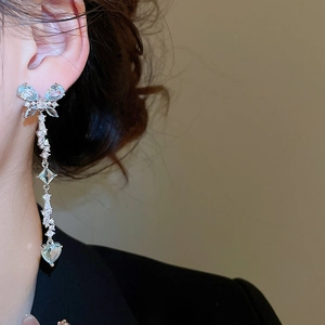 Close-up of dangling butterfly tassel earrings with blue heart zircon on a model