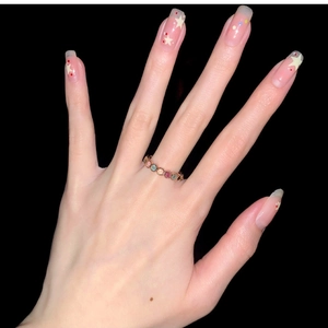 Close-up of a rainbow gemstone gold open ring on a manicured hand with star nail art