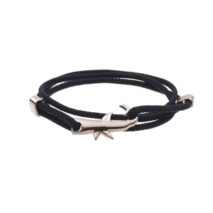 Detail of black woven cord bracelet with silver shark pendant and metal clasp closures