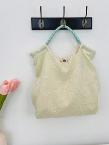 Canvas tote bag with white flower embroidery and green woven handles for summer commute