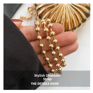 Detail view of the golden metal beaded shoulder strap on a stylish heart-shaped clutch bag