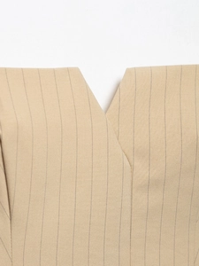 Detail der khakifarbenen Weste mit V-Ausschnitt und feiner Stofftextur