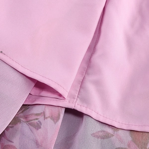 Detail of pink summer dress fabric featuring purple floral print lining and clean stitching