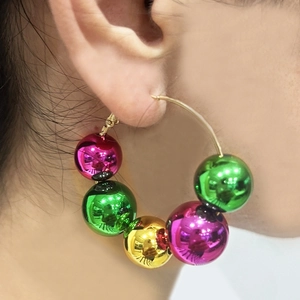 Close-up of gold hoop earring with glossy pink, green and gold beads on a model