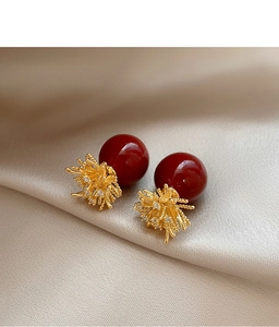 Close-up of vintage red pearl stud earrings with gold coral zircon details on satin